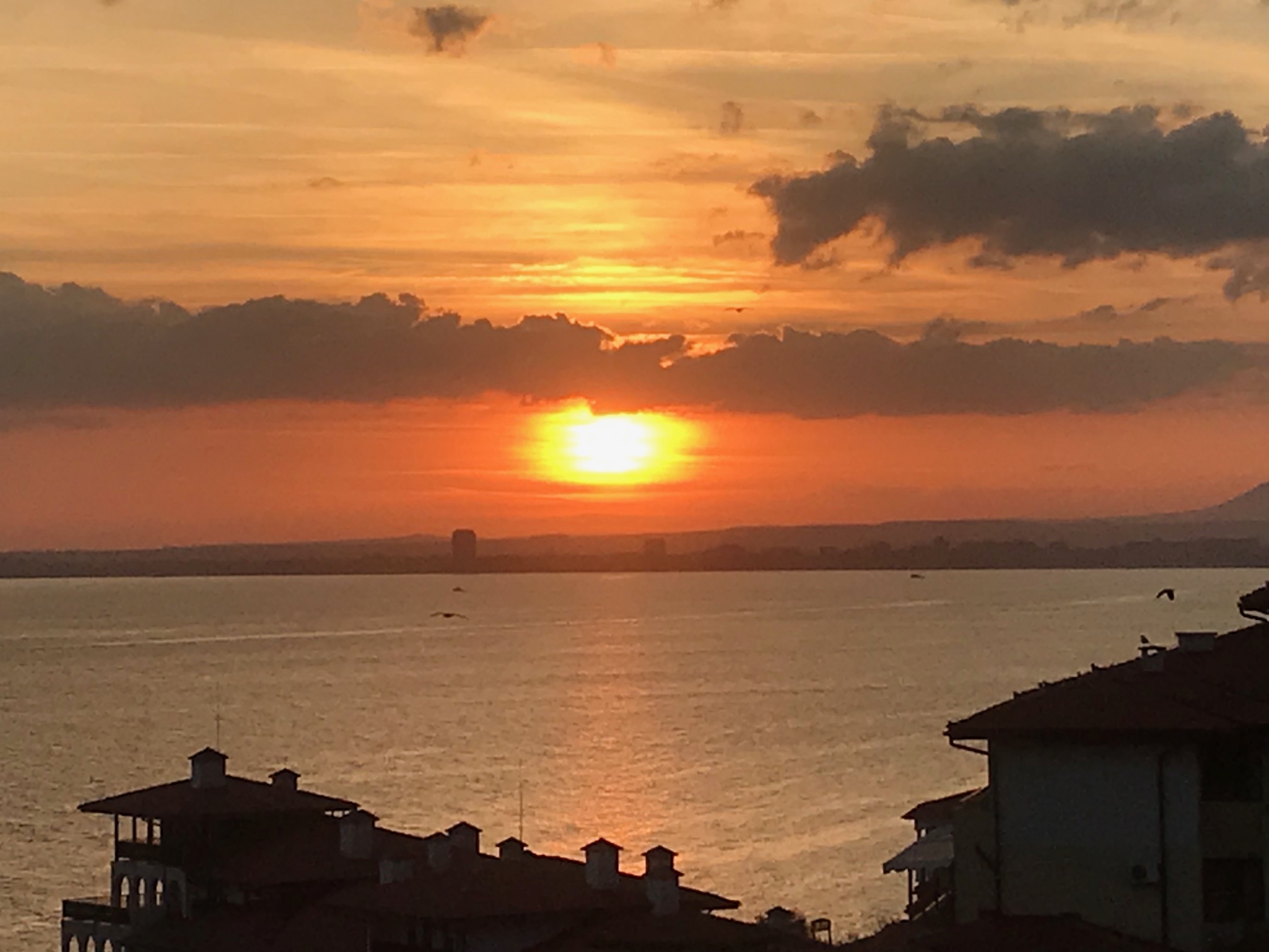 the view from the balcony across the sea at sunset